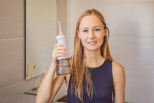 Woman using an oral irrigator in bathroom.