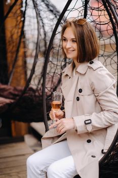 A happy stylish girl In a gray coat walks around the city.