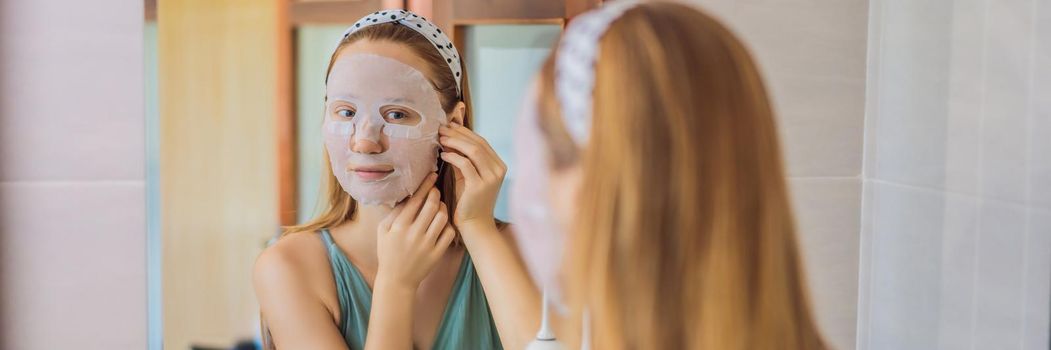 Young red-haired woman doing facial mask sheet. Beauty and Skin Care Concept. BANNER, LONG FORMAT