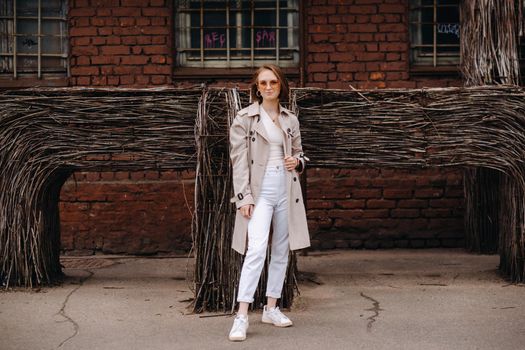 A happy stylish girl in a gray coat walks around the city.