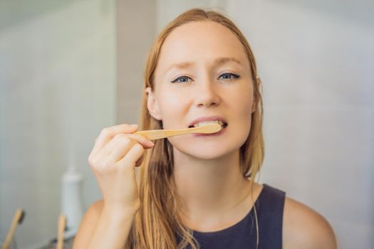 Young and caucasian woman brushing her teeth with a bamboo toothbrush.