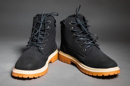 Pair of black winter men's boots on a gray background.