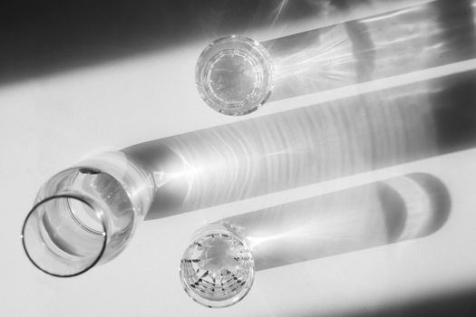 Water in glasses and in a vase on white steel. Shadows hard light. Minimalism