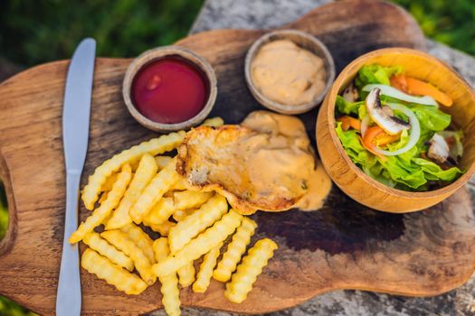 French fries, green salad with champignons and chicken breast. Lifestyle food.