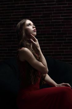 stylish young woman in red dress sitting in a chair.