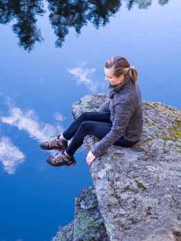 Woman sitting on a rocky ledge above the clouds