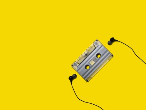 Headphones and old audio cassette on yellow background