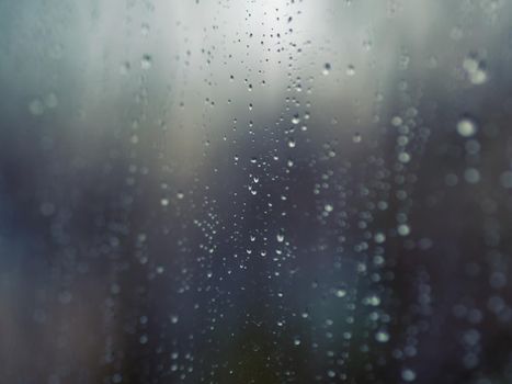 Raindrops on the surface of window glass with a blurred background.