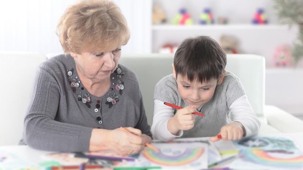 grandmother and grandson paint a rainbow in the nursery.