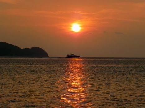 Fishing boat at sea on the horizon during sunset.