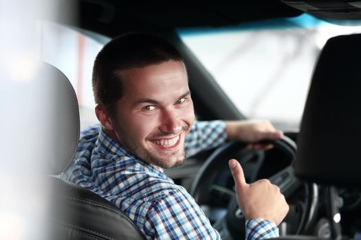 close up. modern man sitting in a car and showing his thumb up.