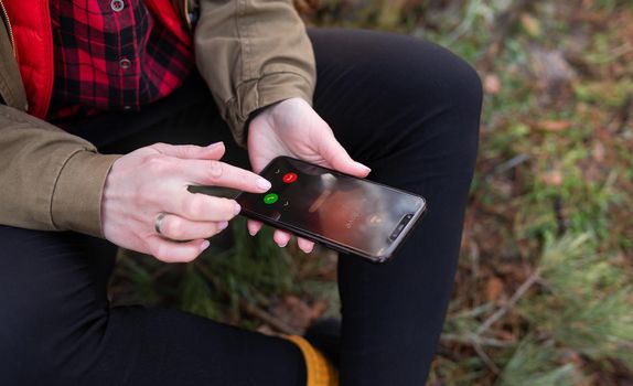 The girl sits on a log in the forest and receives a call from a loved one. Travel, trekking and hiking