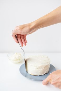 Delicious creamy cake that the girl spreads over the whipped cream with a spatula, the cake is ready for decoration