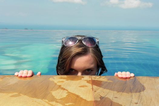 beautiful young european woman in the swimming pool near the ocean, spa, relaxing, tropical, vacation.