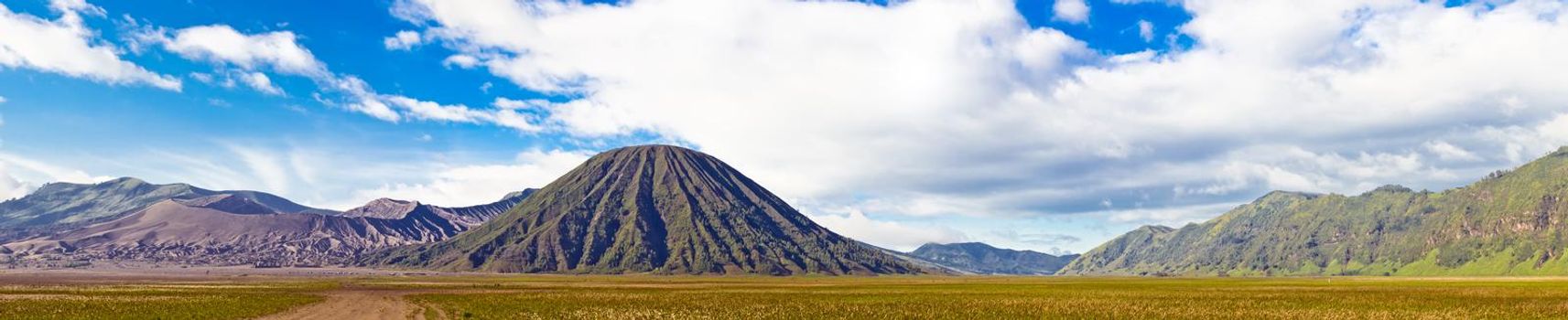 Panoramic view of volcanic landscape against blue sky with clouds. Bromo Tengger Semeru National Park, East Java, Indonesia
