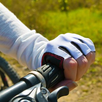 Hand holding a handle bar. Woman riding a bicycle in a park