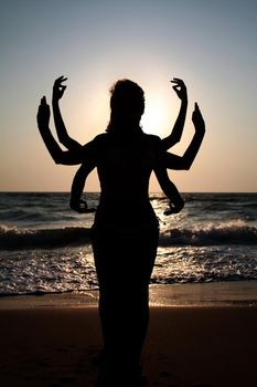 Girls silhouettes standing at the beach with arms raised up. Yoga practice outdoor