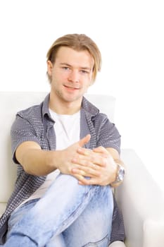 Portrait of happy young man sitting on living room couch, smiling camera