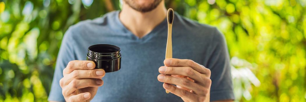 Young man brush teeth using Activated charcoal powder for brushing and whitening teeth. Bamboo eco brush. BANNER, LONG FORMAT