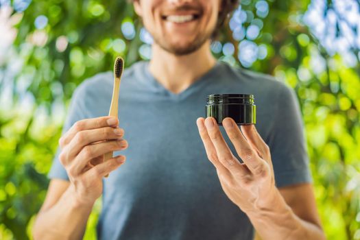 Young man brush teeth using Activated charcoal powder for brushing and whitening teeth. Bamboo eco brush.