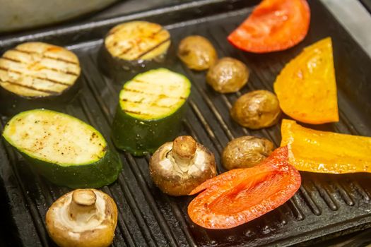 Grilled vegetables: tomatoes, corn, eggplant, zucchini, mushrooms, sweet peppers are prepared in a professional grill machine. Chef grills vegetables in the restaurant kitchen.