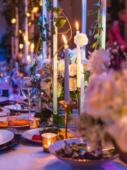 Table served for banquet with candles and floral compositions. Beautiful decorations in blue electric light.