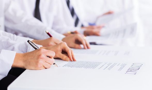 Close-up of male hands with pen over business document