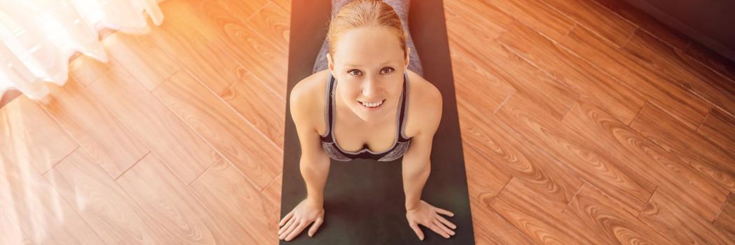 Fitness woman exercising on the floor at home and watching fitness videos in a tablet. People do sports online because of the coronovirus. BANNER, LONG FORMAT