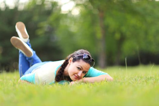 Young pretty woman lying on the grass at summer sunset. Natural happiness, fun and harmony.