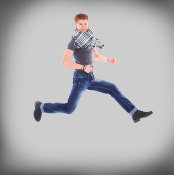 Portrait of an excited young man jumping in air against grey background