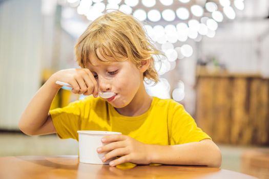 Coronavirus is over. Quarantine weakened. Take off the mask. Now you can go to public places. Boy eating ice cream in a cafe.