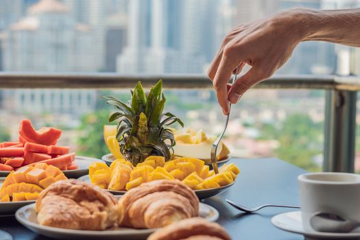 Coronavirus is over. Quarantine weakened. Take off the mask. Now you can go to public places. Breakfast table with coffee fruit and bread croisant on a balcony against the backdrop of the big city.