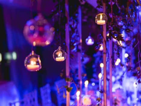 Candles in small glass circlular candle holders handled on strings. Beautiful decorations in blue electric light.