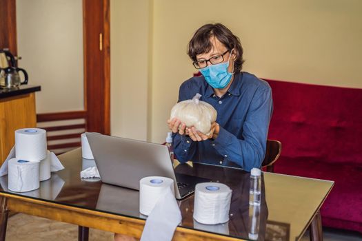 Coronavirus. Man working from home wearing protective mask. quarantine for coronavirus wearing protective mask. Working from home. Cleaning with sanitizer gel. Bought a lot of toilet paper and rice.