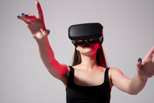 Smiling young woman using the VR goggles and communicating with friends in metaverse. Future technology concept