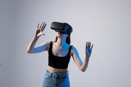 Young woman wearing VR goggles and interacts with cyberspace using swipe and stretching gestures