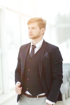 close up. pensive young businessman standing near the office window.