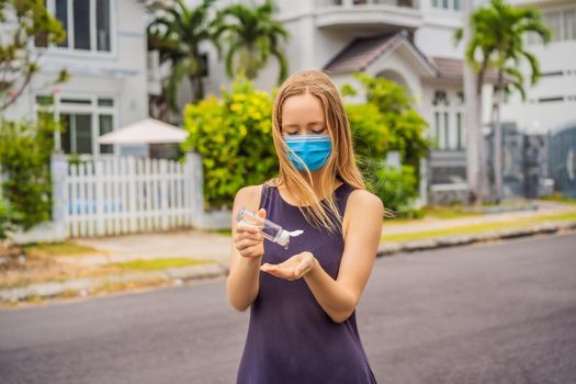 Woman in a small town in a medical mask uses a sanitizer because of a coronovirus epidemic.