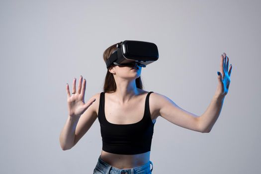 Young woman wearing VR goggles and interacts with cyberspace using swipe and stretching gestures while working on a project