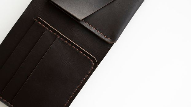 Top view of open brown empty man's black handmade genuine leather wallet with pockets for banknotes, credit cards and monets isolated on white background. Selective focus, copy space, Close up