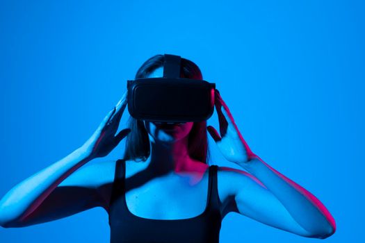 Young attractive curious woman wearing VR goggles and enjoying amazing experience playing and having fun in virtual reality video game