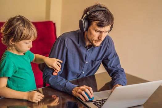 Man is trying to work from home because of the coronovirus epidemic, but his son is stopping him. Self-isolation at home. Children at home schooling. Parents at remote work. Quarantine, self-isolation, coronavirus.