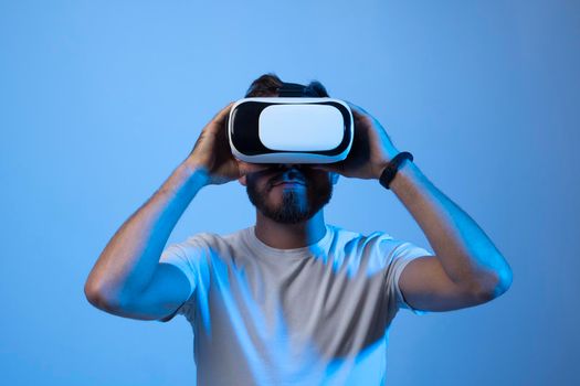 Bearded man in vr glasses, playing video games with virtual reality headset, trying to touch something with a hand