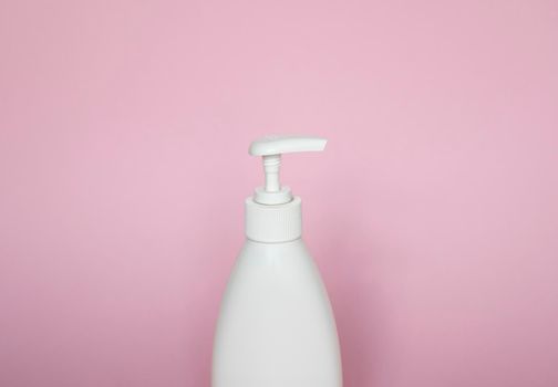 White plastic bottle with shampoo, conditioner or shower gel on a pink background. Mock up template for design