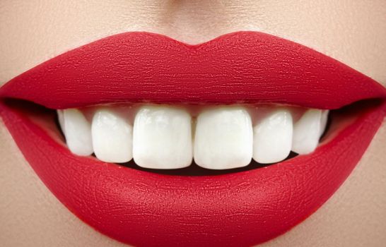 Wide smile of young beautiful woman with perfect healthy white teeth on grey background. Dental whitening, ortodont, care tooth and wellness. Red lipstick makeup on female lips.