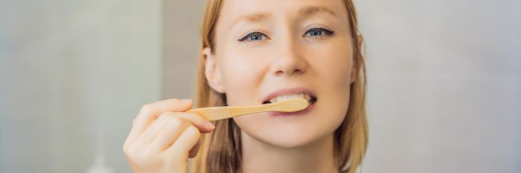 Young and caucasian woman brushing her teeth with a bamboo toothbrush. BANNER, LONG FORMAT