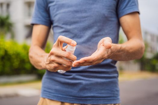 Man in a small town in a medical mask uses a sanitizer because of a coronovirus epidemic.