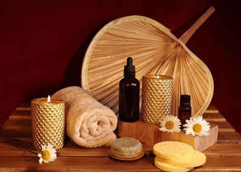 Beautiful Spa Composition. Aromatherapy with Herbal Oil, Natural Soap and Gold Candles. Relaxation Color and Warming Towels on Wooden Background