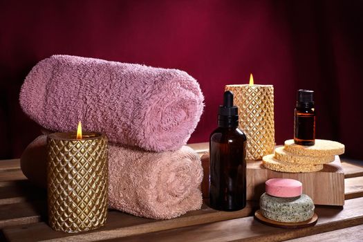 Beautiful Spa Composition. Aromatherapy with Herbal Oil, Natural Soap and Gold Candles. Relaxation Color and Warming Towels on Wooden Background