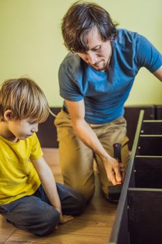 Father and son assembling furniture. Boy helping his dad at home. Happy Family concept.